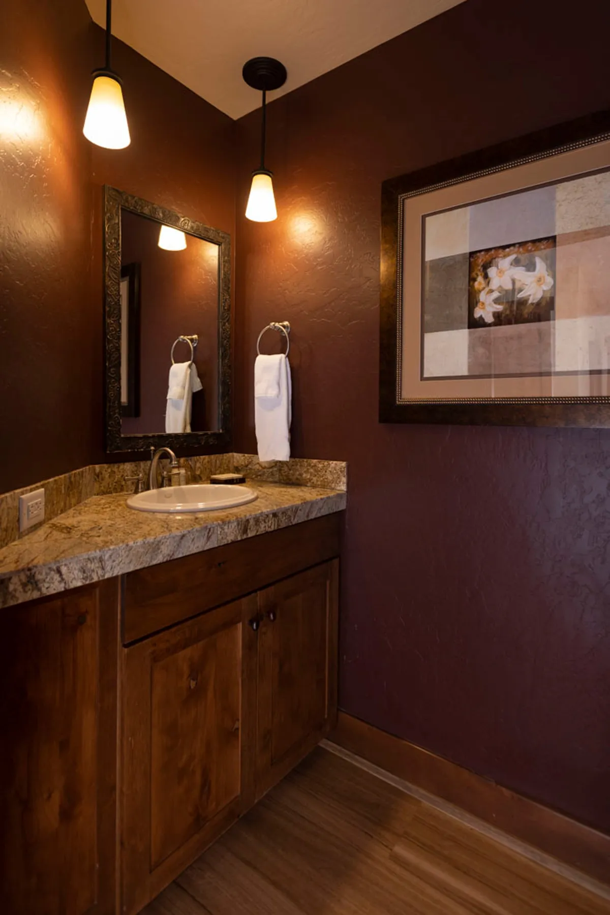 A stylish interior space highlights a sink area with mirrors, tasteful artwork, and warm lighting. The ambiance is cozy and intimate, ideal for self-care rituals or light-hearted exchanges before heading out or settling in for the evening.